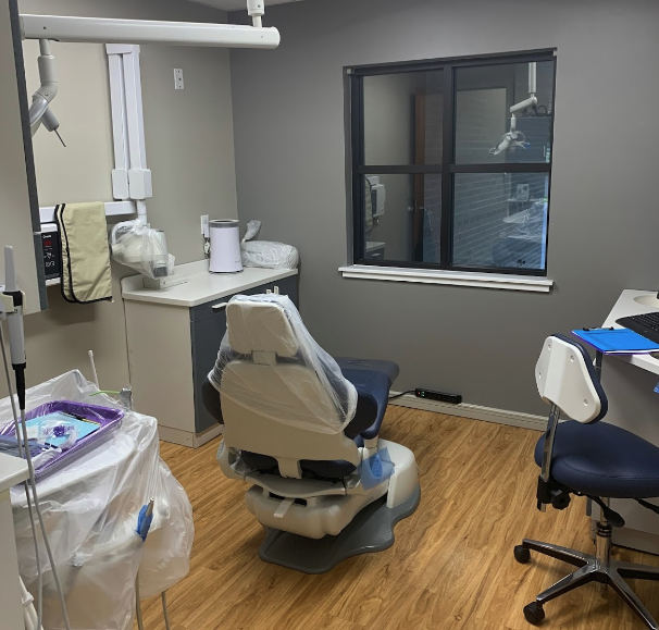 The image shows a dental office interior with dental chairs, equipment, and a desk area with a computer monitor.
