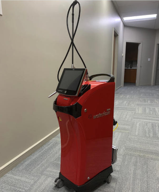 The image shows a red robotic vacuum cleaner with a digital display on its top left corner, parked inside an office building.