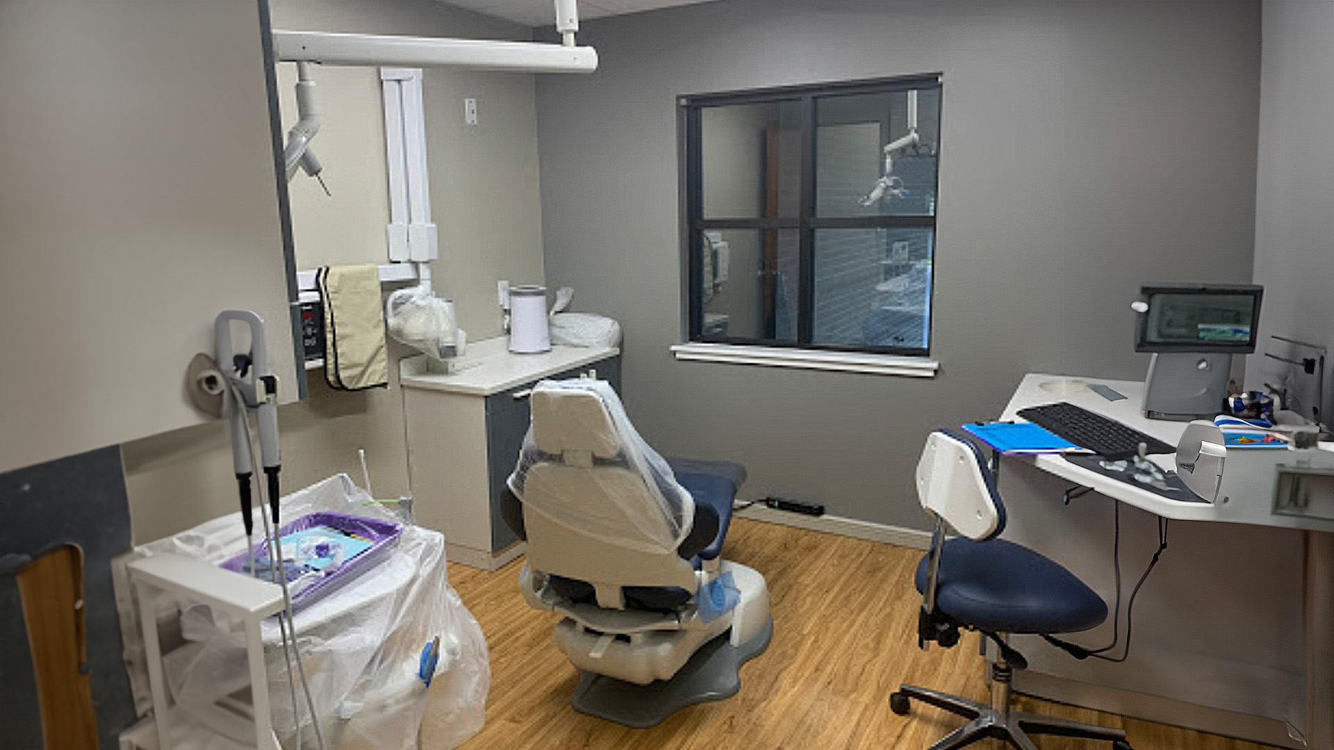 The image shows an interior view of a dental office with dental chairs, equipment, and a reception desk.