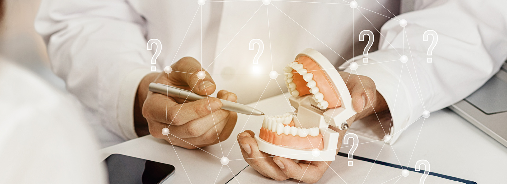 The image shows a person s hand holding a dental model with teeth, while another hand appears to be writing on paper with a stylus.