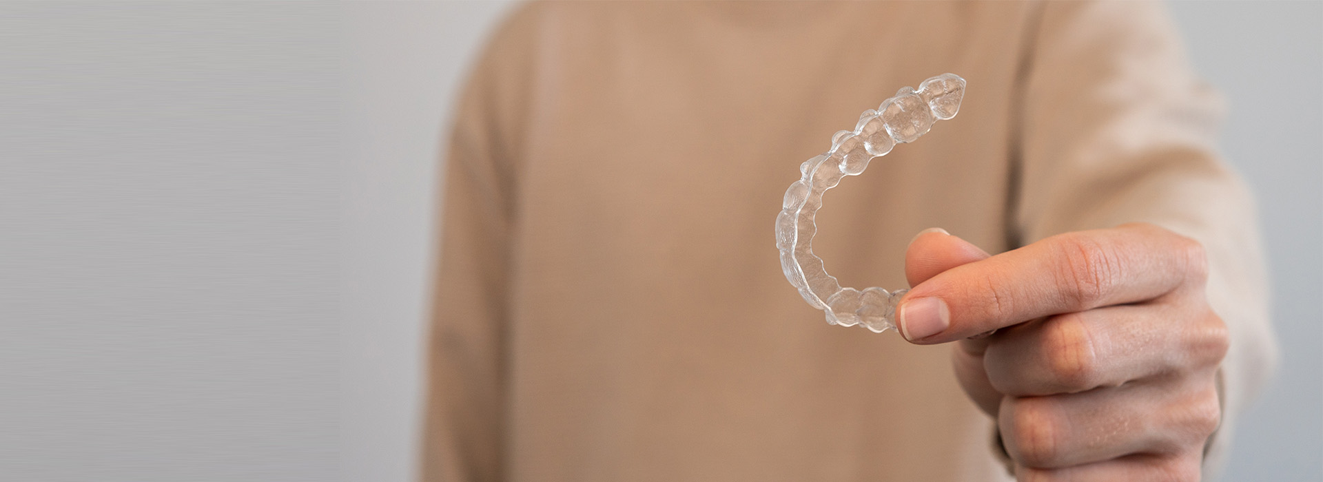 The image shows a person s hand holding a transparent bubble with a visible pattern inside, against a blurred background.