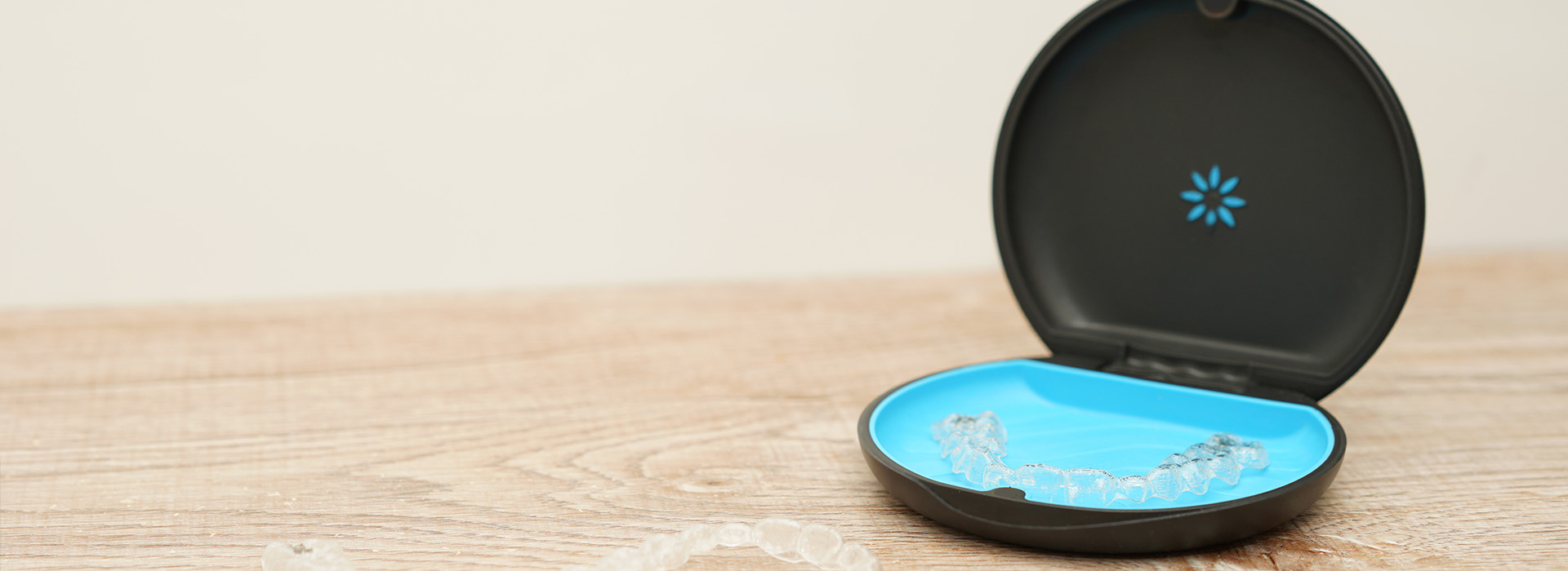 The image shows a smartphone charging station with a blue interior, placed on a wooden surface against a white background.
