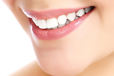 The image displays a close-up view of a person s face with a focus on their teeth, which are white and appear to be well-maintained, set against a blurred background that does not provide any additional context.