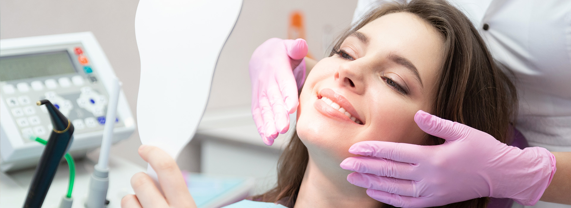 The image shows a woman seated in a dental chair with a dentist performing a procedure on her teeth.