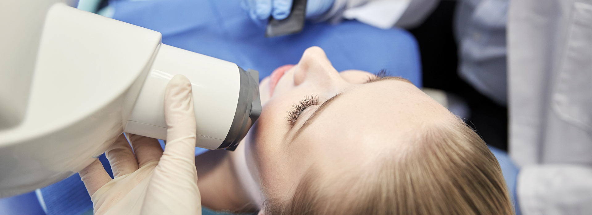 A person receiving dental treatment with a dentist using a microscope to examine their teeth.