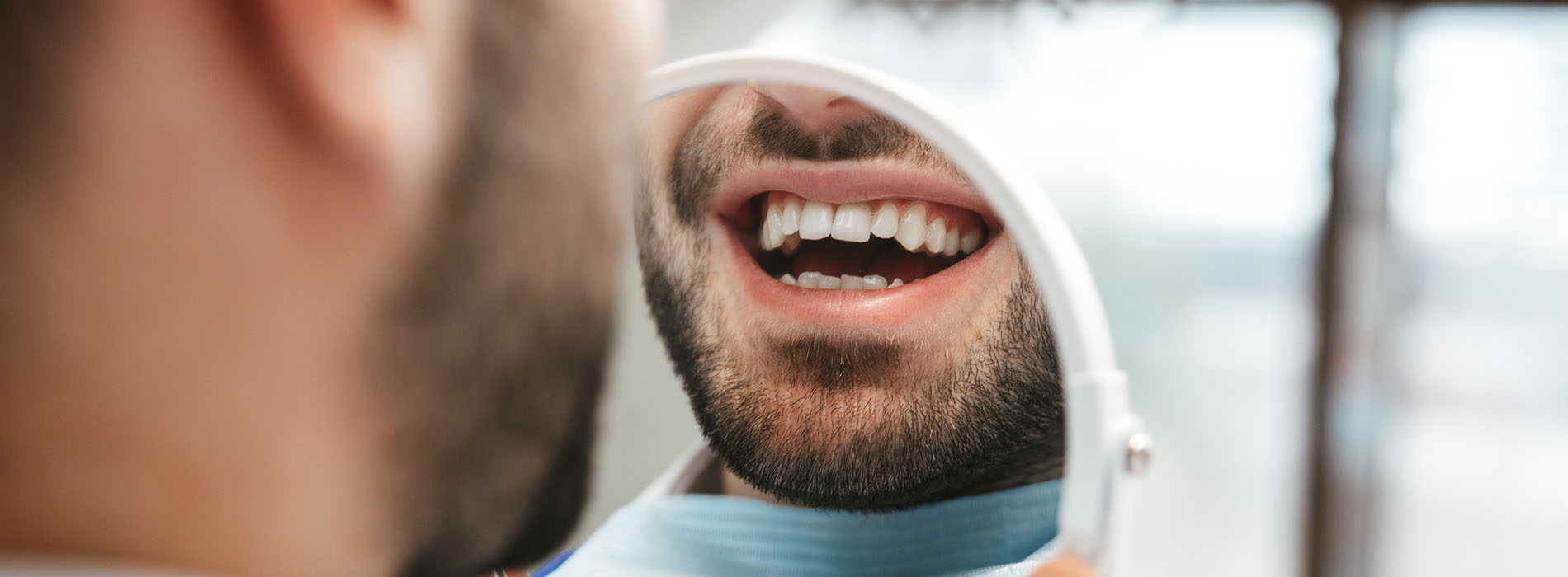 The image shows a man with his mouth open, likely speaking or singing, while another person appears to be looking at him from behind, possibly indicating an interaction between them.