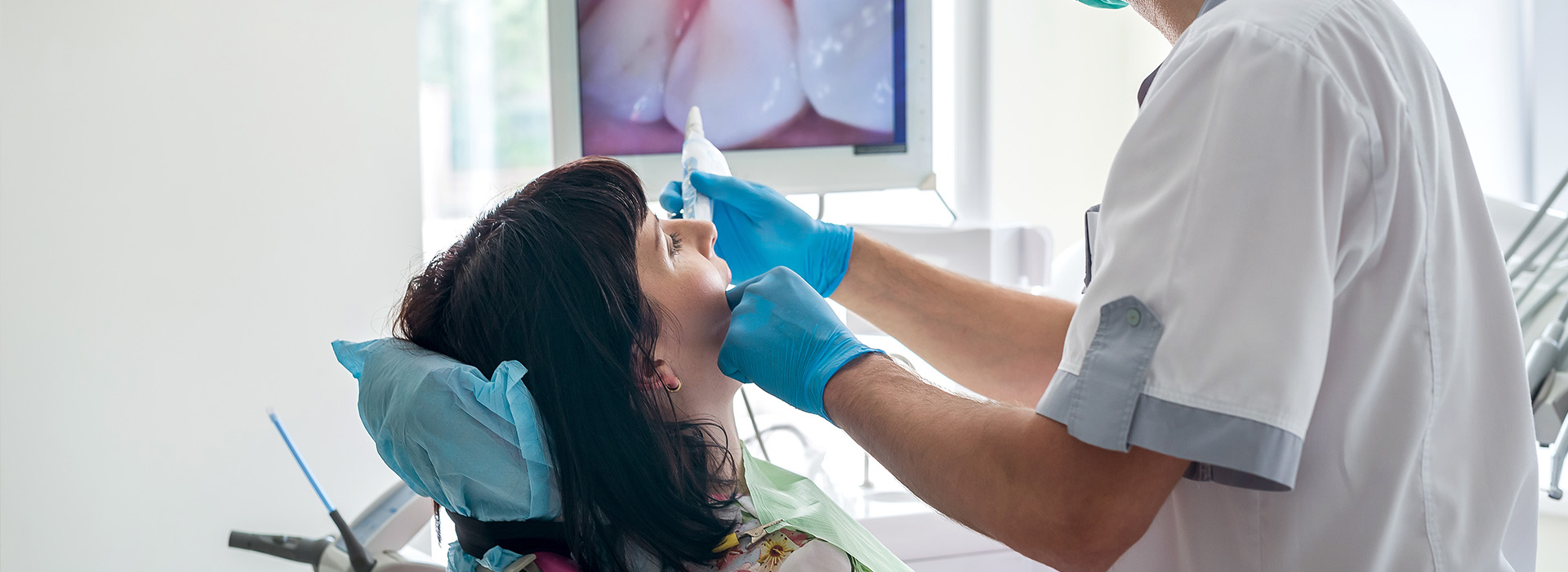 The image shows a dental professional performing a procedure on a patient s teeth, with the dentist wearing protective eyewear and using dental instruments.