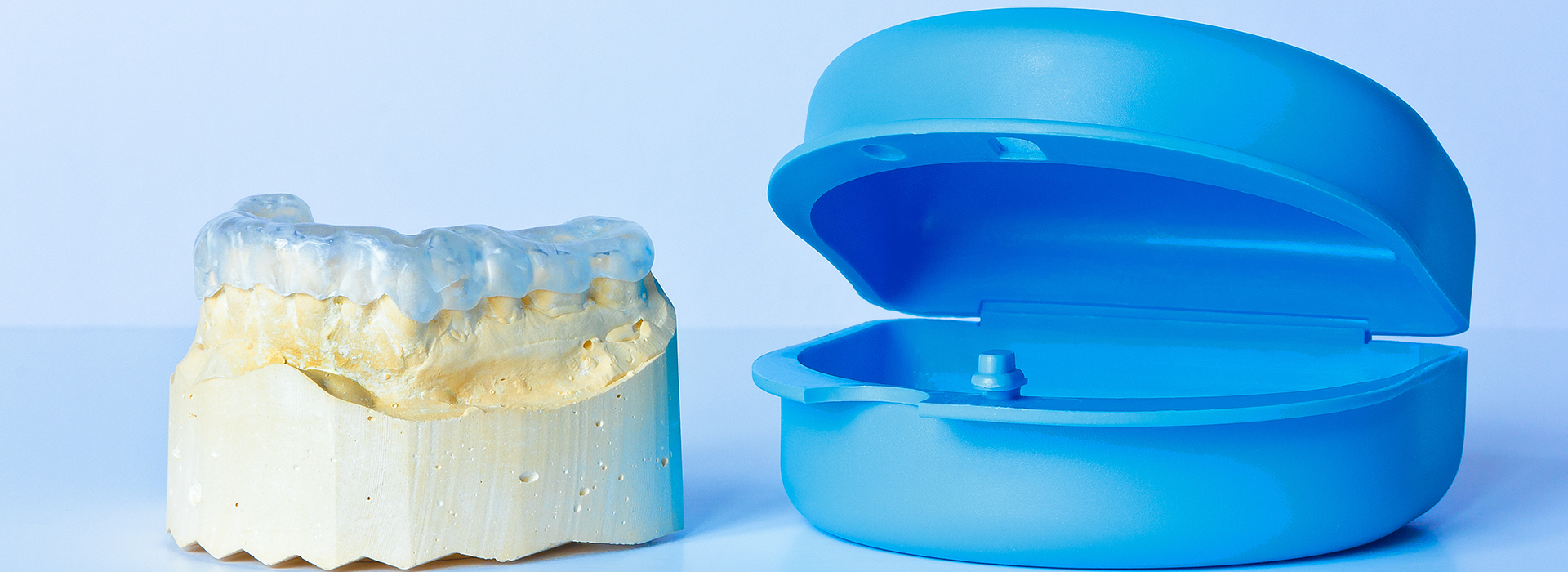 The image shows two dental implants one is a physical model with a yellowish-brown surface, and the other appears to be a blue 3D printed representation of a similar object.