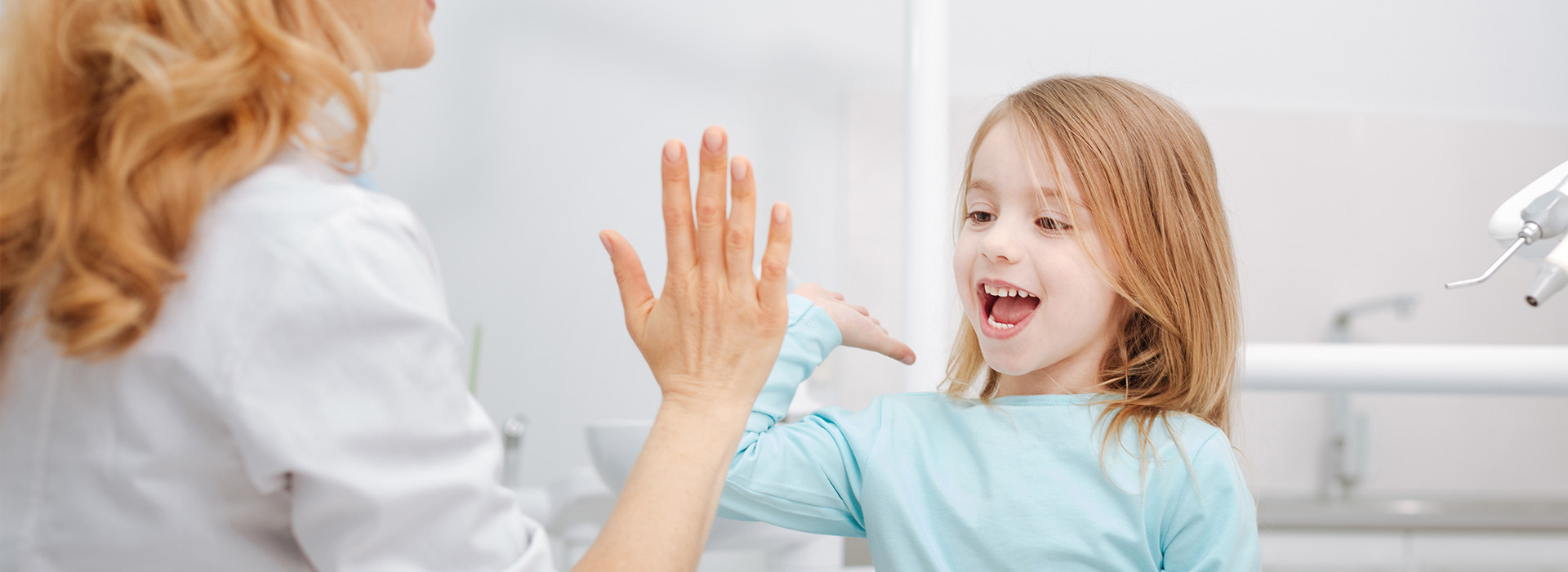 A woman and a young girl are interacting in a bathroom setting, with the woman gesturing towards the child.