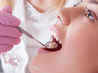 The image shows a dental professional performing oral care on a patient using specialized equipment, with a focus on the process of teeth whitening or cleaning.