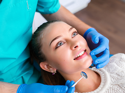 A dental hygienist performing a teeth cleaning procedure on a patient's mouth.